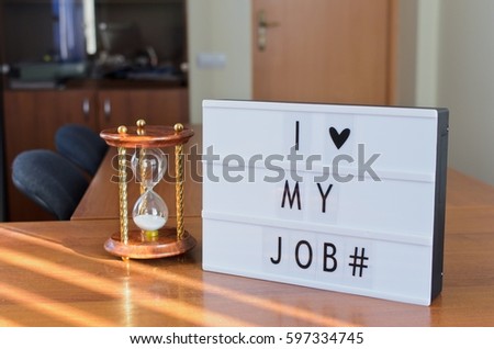 'I love my job' letters shown in lightbox put on the desk in office interior.