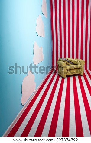 A surrealistic picture of a bright colored location with red and white strings, contrasting with blue walls and white clouds glued to it.