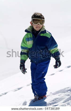 Child walking on snow with ski suit mask and gloves