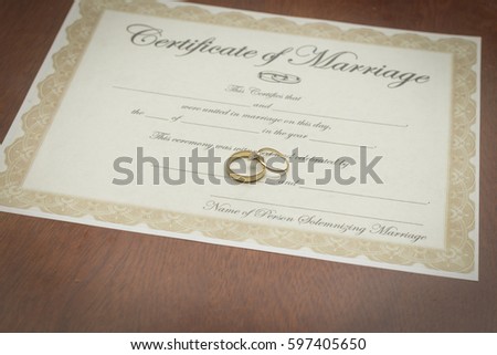 gold wedding rings on a marriage certificate  Royalty-Free Stock Photo #597405650