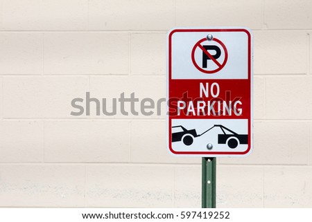 No Parking - Tow Zone sign against off white brick wall