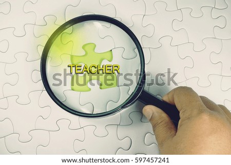 Education concept – magnifying glass on white puzzle with a green space.