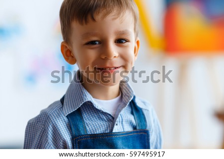 Close-up portrait of cute, smiling, caucasian white, three years old boy in blue shirt and jeans apron. Child with beautiful eyes, concept of early childhood education, happy family or  parenting Royalty-Free Stock Photo #597495917