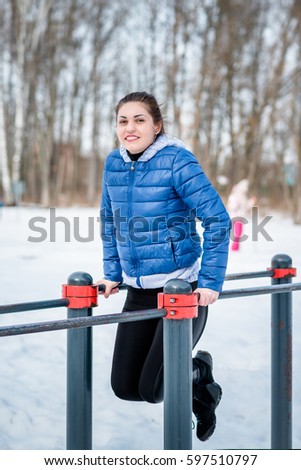 A beautiful young girl is engaged in stretching and gymnastics in the winter forest, on the sports field.