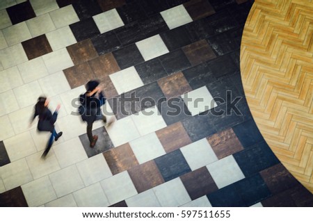 Blurred Abstract Background. Silhouettes of two people walking in a public building hall top view. Motion blur technique of low speed shot. Blur silhouettes of people's. Low speed shutter shot.