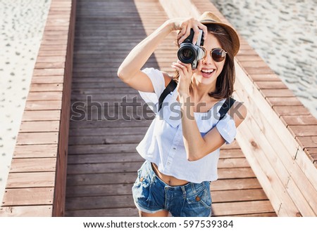 Young beautiful tourist woman taking photographs with digital retro styled photo camera