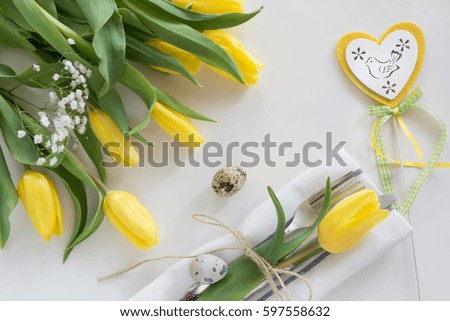 Easter concept with copy space for your Happy Easter wishes. Decorative easter place setting with yellow tulip, a quail egg on a white background.