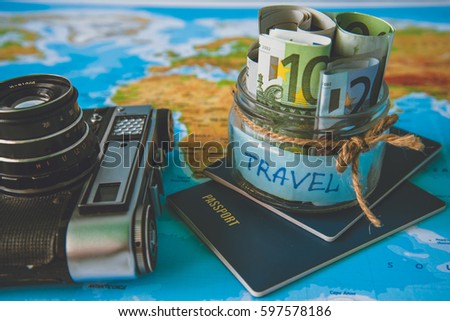 Vacation budget concept. Vacation money savings in a glass jar on world map with retro camera and passport