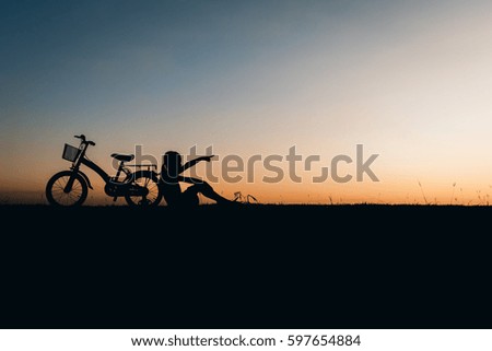 Silhouette of girl with bicycle  at the sky sunset, color of vintage tone and soft focus.