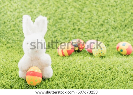 Easter bunny toy and Easter eggs on green grass