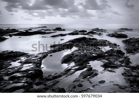 Beautiful long exposure shot of seascape rock beach in black and white. A slow shutter speed was used to see the movement. (Soft focus due to long exposure shot)