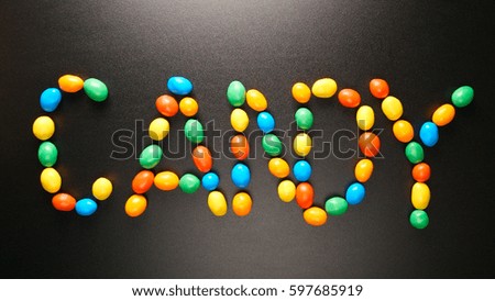 TOP VIEW: Candy letters by colorful candies on black background