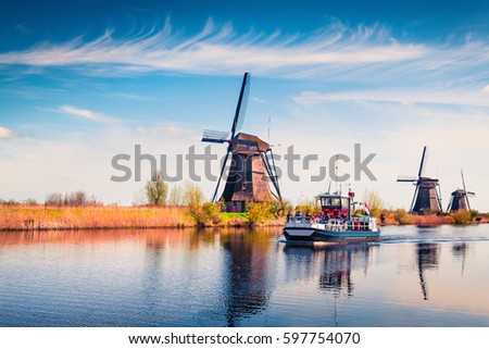 Famous windmills in Kinderdijk museum in Holland. Sunny spring morning in countryside. Colorful outdoor scene in Netherlands, Europe. UNESCO World Heritage Site. Artistic style post processed photo.