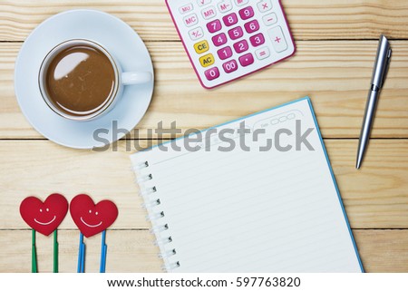 Simple workplace with a cup of coffee, notebook paper, pen,Paper clip and calculator on wood table