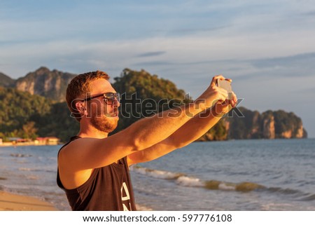 Young man tourist is photographed on the beach