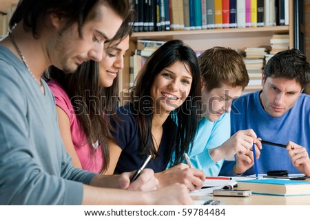 Group of young students working and studying in a college library, smiling girl looking at camera.