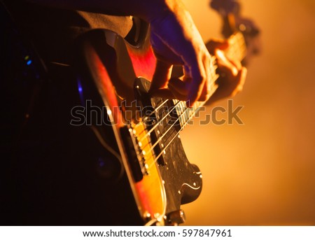 Close-up photo of bass guitar player, soft selective focus, live rock music theme