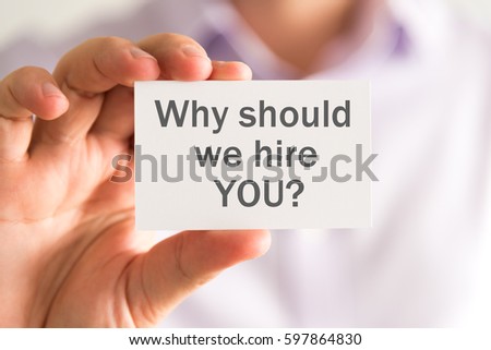 Closeup on businessman holding a card with WHY SHOULD WE HIRE YOU ? message, business concept image with soft focus background