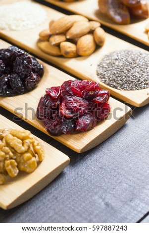 sun dried organic fruits, nuts and oil seeds on bamboo serving tray, black wooden table background