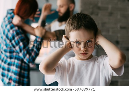 Sad child covering his ears with hands during parents quarrel. Man about to beat his wife Royalty-Free Stock Photo #597899771