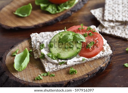 Healthy eating or dieting scene with crisp bread and fresh tomatoes and cucumber. Wooden table, rustic scene.