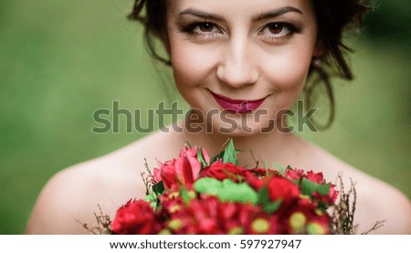 Bride with shiny dark hair holds red wedding bouquet