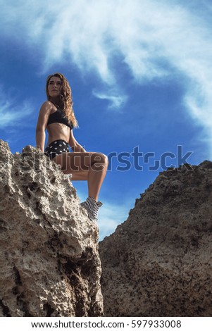 Young girl in bikini sitting on a rock
