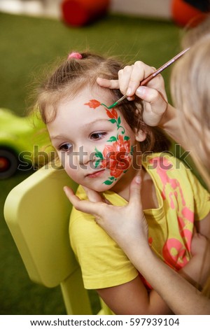 The animator draws a children's makeup drawing on the face of a child
