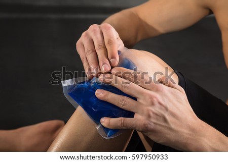 Close-up Of A Person Applying Ice bag On An Injured Knee In The Gym