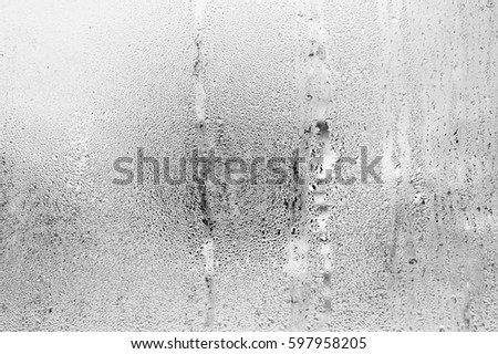 Black and white background of the condensate flowing water on the window glass