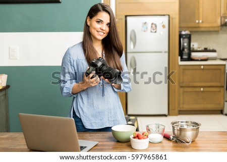 Gorgeous young female photographer taking some photos of food in a kitchen