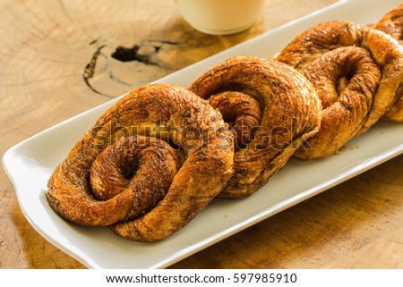 Zeeuwse bolussen with dark brown sugar is a sweet pastry of Jewish origin from the Dutch province of Zeeland, on the whitw plate and table of wooden background. Royalty-Free Stock Photo #597985910