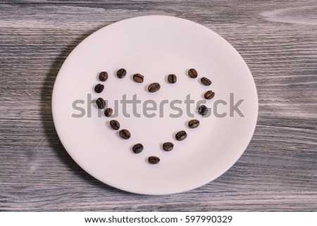 Coffee heart on white plate, wooden background