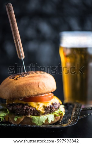 Burger, fried potatoes and beer on a dark background close-up. Street food. Fast food. Royalty-Free Stock Photo #597993842
