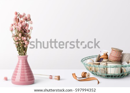 Home interior table scene, front view, with decor elements, flowers, spools, and blank copy, logo space on white background.