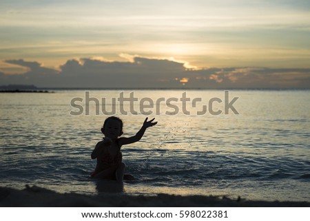 Happy little girl playing at the sunset beach