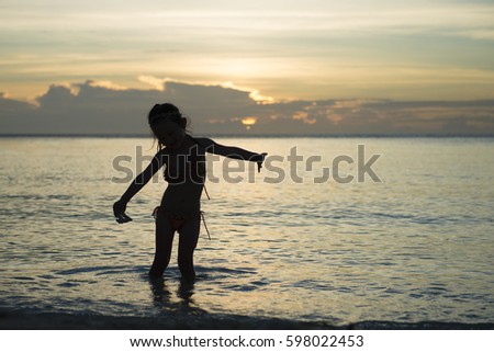 Happy little girl playing at the sunset beach