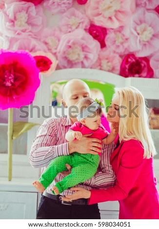 Mother in pink jacket kisses little girl tender standing in pink room