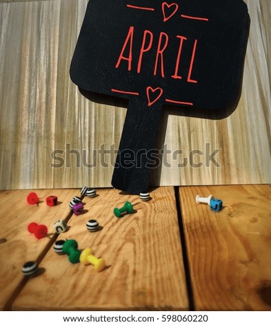 APRIL word on the blackboard with wooden background and colorful cubes on wooden board