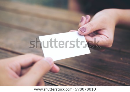 Businessman giving  business card to businesswoman with wooden table background