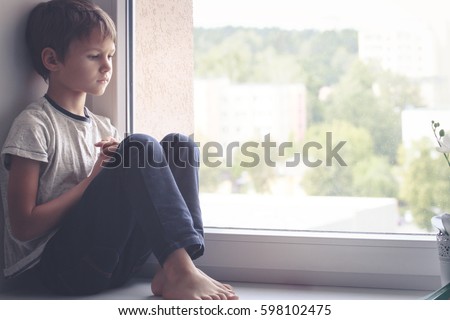 Sad kid sitting on window shield and looking out the window Royalty-Free Stock Photo #598102475