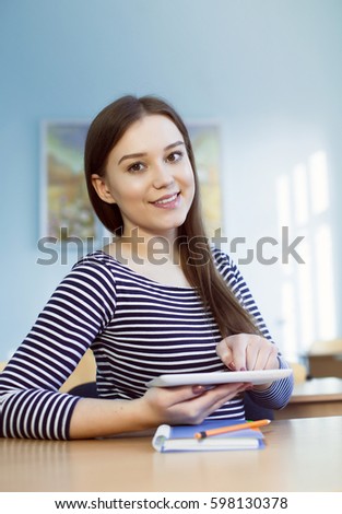attractive girl rejoices at the table in a school