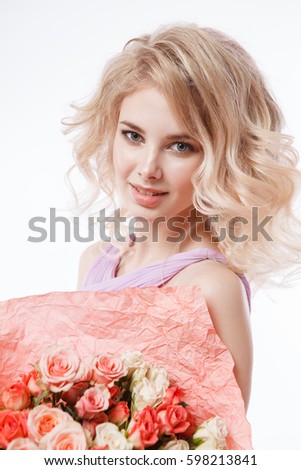 Portrait of beautiful curly blondy woman with perfect make-up. Holding bouquet
