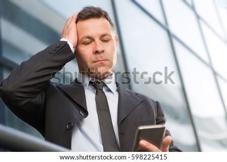 Frustrated businessman reading a text message on cell phone