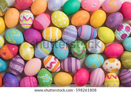 Many Bright and Colorful Easter Eggs Filling the Background.  They are hand-painted or dyed.  It's a closeup, or macro, with a horizontal top view in flat lay style that can be used vertical.