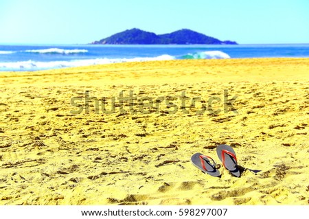 Flip Flop On Paradise. A pair of red sandals on beach sand, Praia do Campeche with an island at horizon on Florianópolis Southern Brazil     