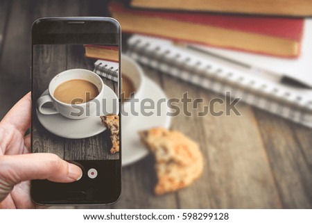 Taking a photo by Finger Pressing on Smartphone for Photograph Hot Coffee on Wood Background with Copy Space in Relax Concept, Image for Beverage Advertise or Social Media with Drink Concept