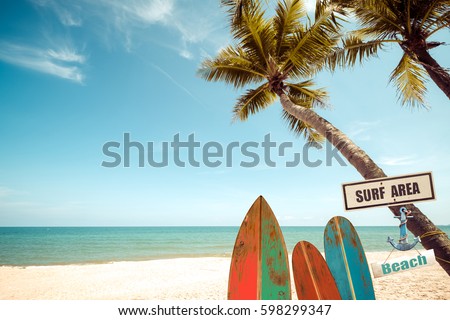 Vintage surf board with palm tree on tropical beach in summer. vintage color tone Royalty-Free Stock Photo #598299347