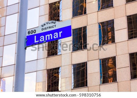 Lamar street sign in downtown Houston, Texas with a skyscraper in the background.