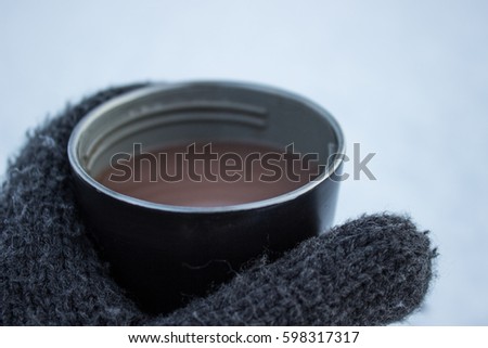 Glove holding a mug of hot chocolate 